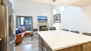 Een moderne keuken met een groot kookeiland, zithoek met een bank en stoelen, en een open haard.