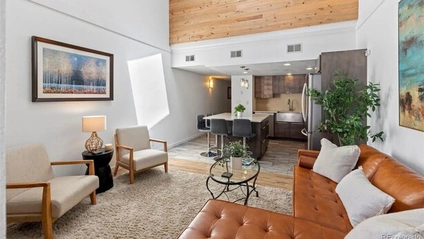 Een moderne woonkamer met een hoge plafond, een eethoek en een keuken.