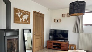 Un salon doté d’un poêle à bois, d’un téléviseur à écran plat, d’une table à manger en bois et d’une carte du monde accrochée au mur.
