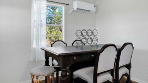 Een eetruimte met een tafel, stoelen en een airconditioning.