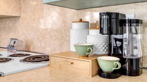 Een keuken met een fornuis, koffiezetapparaat en opslagpotten.
