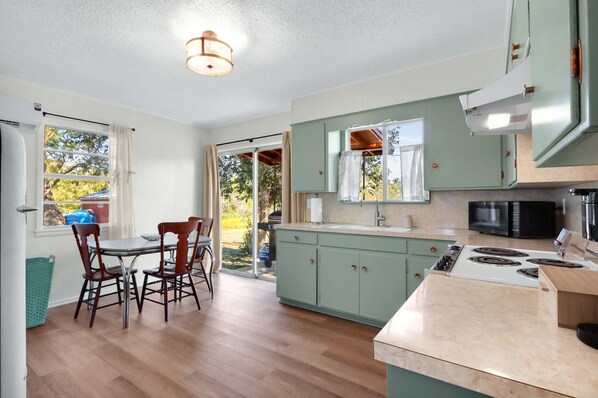 A kitchen with a dining area, a stove, a microwave, and cabinets.