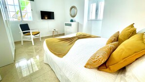 A hotel room with a bed, a chair, a TV, a small table, and a window.