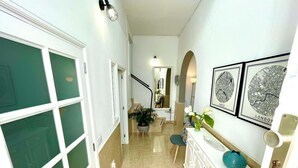 A hallway with a white cabinet, a potted plant, and framed maps of Paris and London.