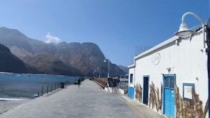 A coastal walkway with a building featuring a blue door and a clock.