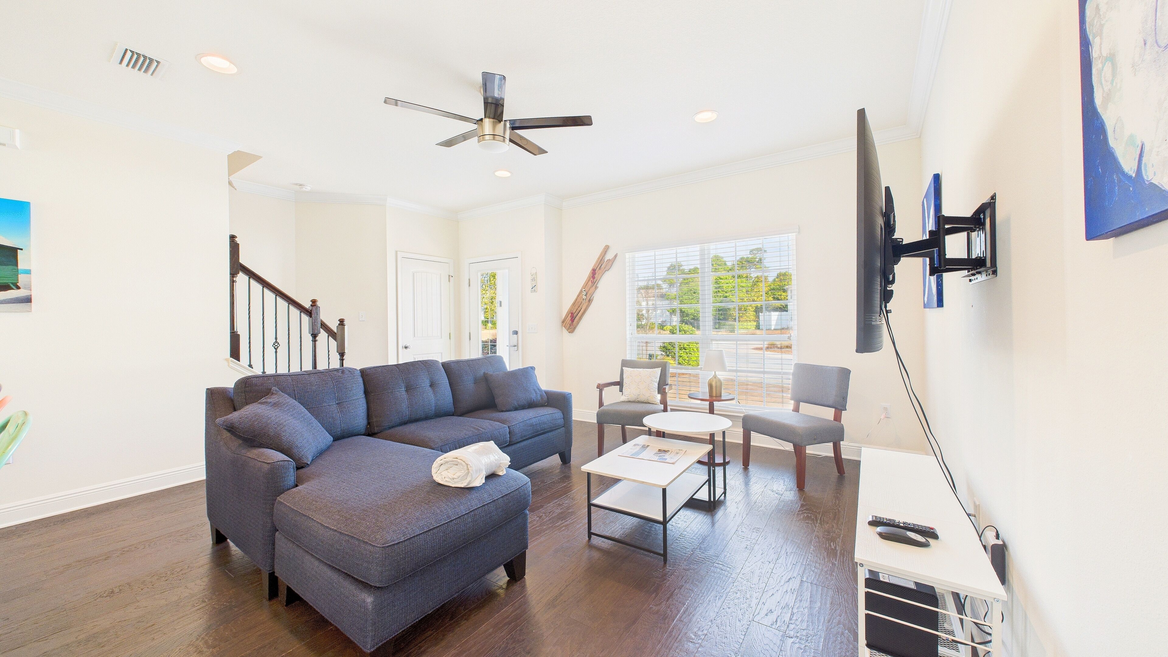 A living room with a blue sofa, a coffee table, and a TV mounted on the wall.