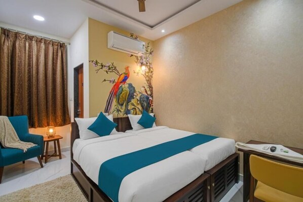 A hotel room with a bed, a chair, a small table, and an air conditioning unit. - Hotel Broholi Inn Near Hafeezpet Railway Station (Hyderabad)