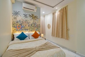 A hotel room with a bed, a mural on the wall, an air conditioner, and curtains. - Hotel Broholi Inn Near Hafeezpet Railway Station (Hyderabad)