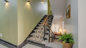 Eine Treppe mit gemusterten Stufen und einer Handläufe, die zu einem Zwischenpodest mit einer Lampe und einem gerahmten Bild an der Wand führt.