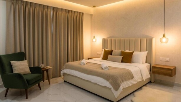 Ein Hotelzimmer mit einem großen Bett, einem grünen Sessel und einem Nachttisch.