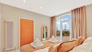 A hotel room with a large bed, a wooden door, a radiator, and a view of the outdoors. - The Retreat at Glenridge House - North East Escapes (Wooler)