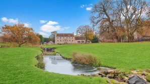 A stone building with a grassy field and a small stream. - The Retreat at Glenridge House - North East Escapes (Wooler)
