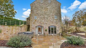 A stone building with a central entrance, a small upper window, and a staircase leading up to a balcony. - The Retreat at Glenridge House - North East Escapes (Wooler)