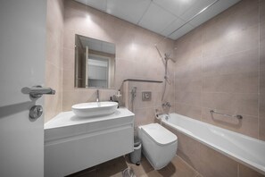A modern bathroom with a white sink, mirror, and bathtub. - Stayshort - Damac Hills Sleeps 2 Near Golf Courses (Dubai)
