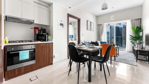 A modern kitchen with a built-in oven and a dining area with a table set for four. - Stayshort - Business Bay for 4 People With a Fabulous Pool (Dubai)