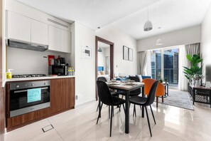 A modern kitchen with a built-in oven and a dining area with a table set for four. - Stayshort - Business Bay for 4 People With a Fabulous Pool (Dubai)