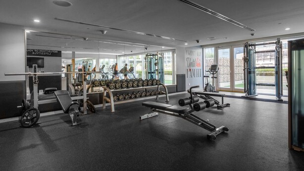 A modern gym with weightlifting equipment, a bench, and a rack of dumbbells. - Stayshort - Business Bay for 4 People With a Fabulous Pool (Dubai)