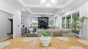 A modern living room with a wooden dining table, a fireplace, and a sofa. - New! Modern Luxurious Woodland Retreat 5 Bedroom Home (Scottdale)