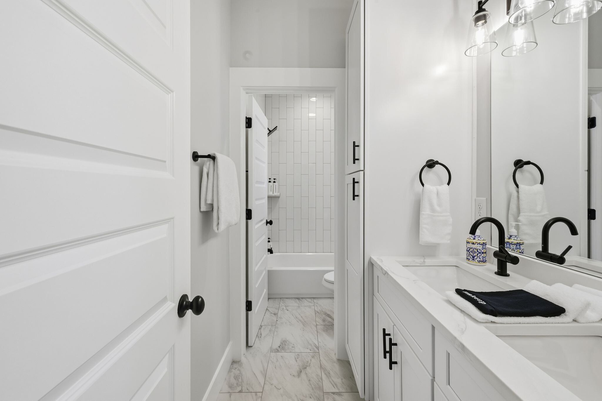 A modern bathroom with a white vanity, a black faucet, and a mirror.