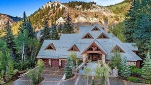 A mountain lodge with a steep roof, stone exterior, and a front porch. - Fairway Drive Retreat 6 Bedroom Home (Avon)