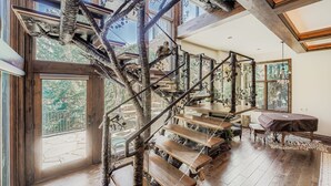 A wooden staircase with a natural design, leading to a balcony with a view of trees. - Fairway Drive Retreat 6 Bedroom Home (Avon)