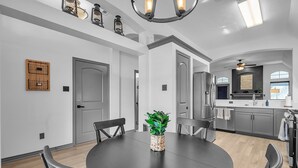 A modern kitchen with grey cabinets, a central island, and a dining area with a round table and chairs. - Relaxing College Station Retreat With Hot Tub 3 Bedroom Home (College Station)