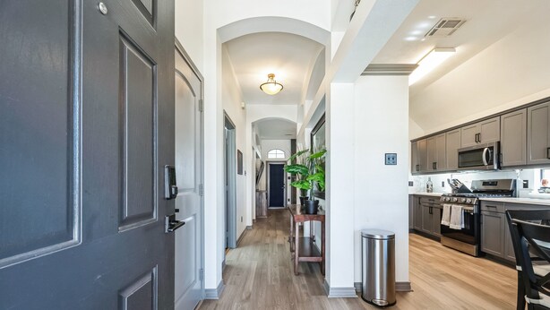 A modern kitchen with stainless steel appliances, a wooden floor, and a central island. - Relaxing College Station Retreat With Hot Tub 3 Bedroom Home (College Station)