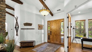Une pièce spacieuse avec un plancher en bois, une grande porte en bois, un lustre et une décoration murale rustique.