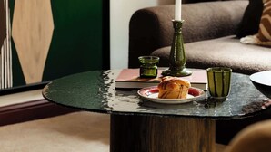 A round table with a candle, a plate with food, and two green glasses.