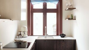 A kitchen with a double sink, a coffee maker, and a window with a blue valance.