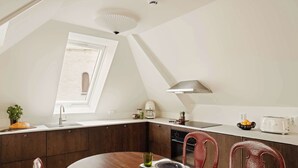 Eine moderne Küche mit dunklen Holzschränken, einer weißen Arbeitsplatte und einem Essbereich mit einem runden Tisch und roten Stühlen.