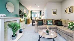 A modern living room with a sectional sofa, a round coffee table, a fireplace, and a dining area in the background. - Stunning Riverside Home in Chester with Parking! (Chester)