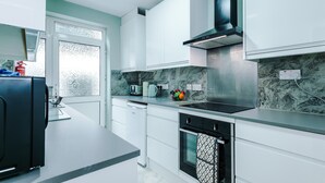 A modern kitchen with white cabinets, a black stove, and a marble backsplash. - Stunning Riverside Home in Chester with Parking! (Chester)