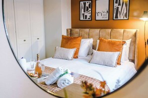 Una habitación de hotel con cama, almohadas, una botella, vasos y toallas.