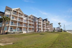 Ein mehrstöckiges Hotel mit Balkonen, einem Rasen und Palmen.