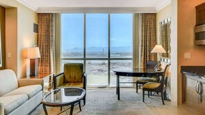 Una habitación de hotel con un ventanal grande, un sofá, una mesa de comedor y una cocina.