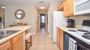 A modern kitchen with wooden cabinets, a white refrigerator, a stove, and a sink.