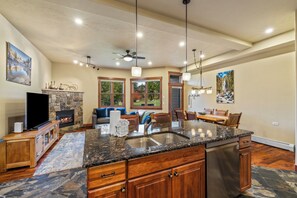 A spacious kitchen with granite countertops, a built-in dishwasher, and a stone fireplace. - Enjoy the Rocky Mountains from the Comfort and Convenience of Moraine Townhome! (Steamboat Springs)