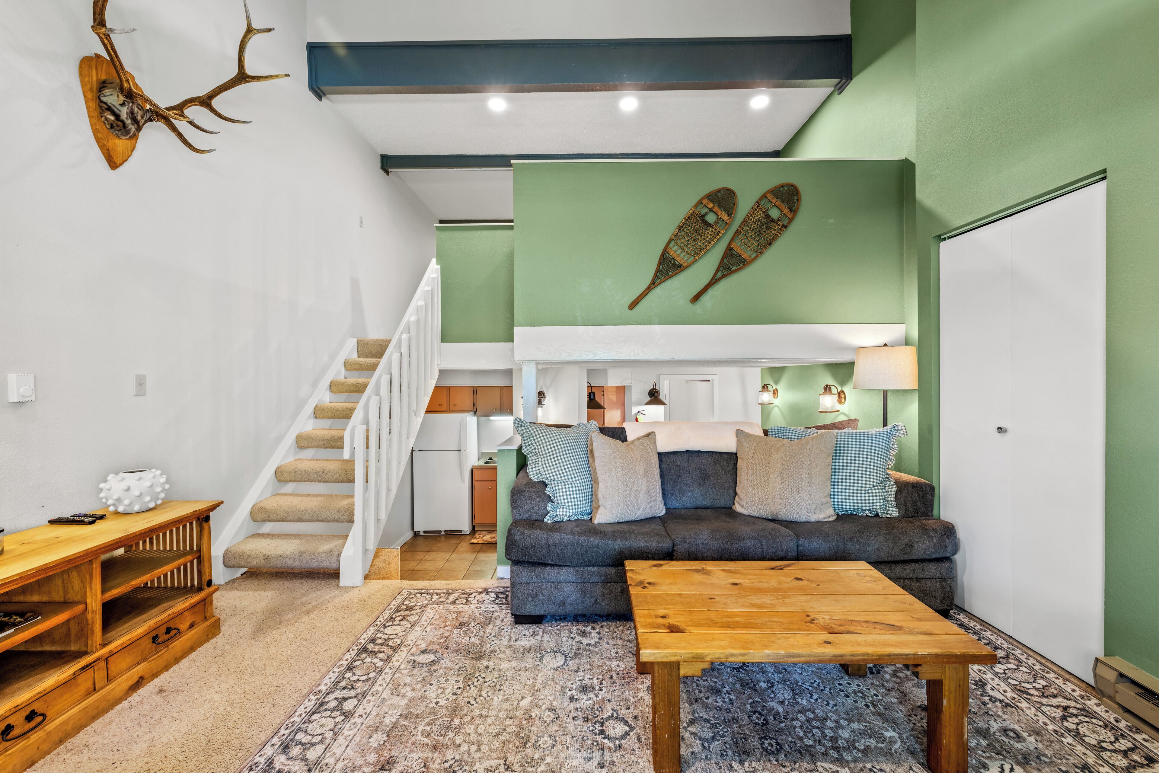 A living room with a sofa, coffee table, and a staircase leading to an upper level.