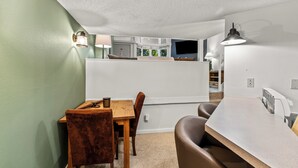 A compact living space with a dining area, kitchenette, and a TV mounted on the wall.