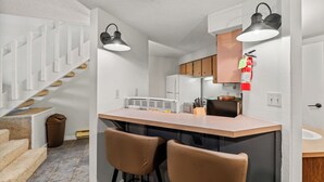 A modern kitchen with a central island, bar stools, and pendant lighting.