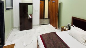 Une chambre d’hôtel équipée d’un lit, d’un ventilateur de plafond, d’une armoire et d’une salle de bain avec un miroir et des toilettes.