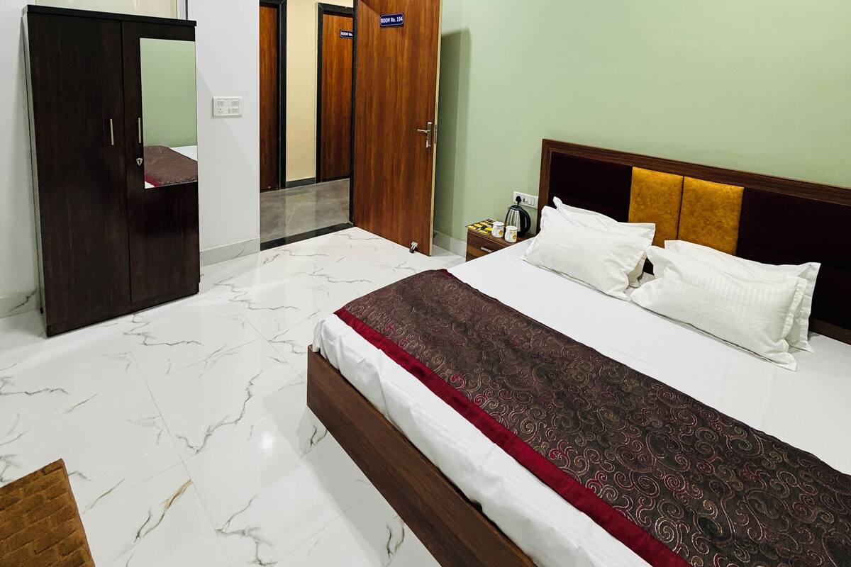 A hotel room with a bed, a ceiling fan, a wardrobe, and a door.