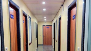 Un long couloir étroit, avec des portes de chaque côté, chacune portant une plaque indiquant le numéro de la pièce.