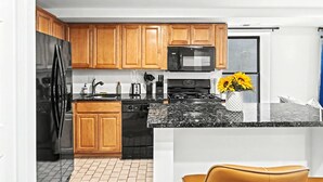 A modern kitchen with wooden cabinets, a black refrigerator, a microwave, a stove, and a sink. - Posh Center Spot: 2BR Fits 6 Guests Near Sights (Philadelphia)