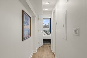 A hallway with a bed, a painting, and a view of buildings. - Prime 2BR Sleeps 6 Oasis | Near The Liberty Bell (Philadelphia)