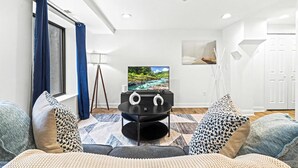 A living room with a flat-screen TV, a ceiling fan, and a painting on the wall. - Posh Center Spot: 2BR Fits 6 Guests Near Sights (Philadelphia)