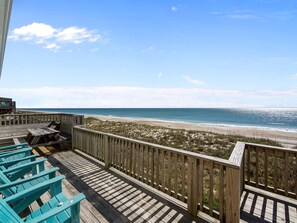Une terrasse en bois avec des chaises bleues donnant sur une plage.