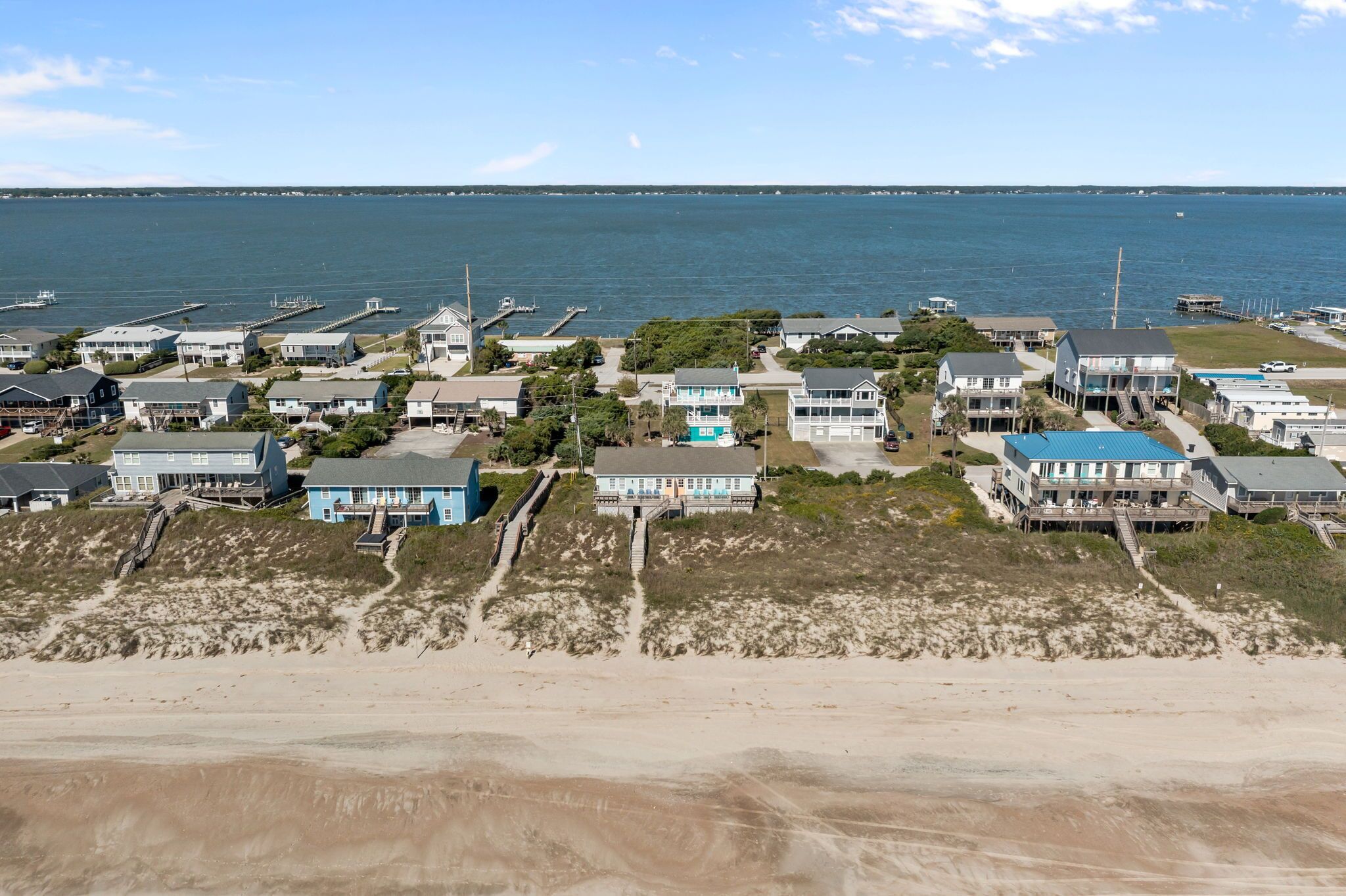 A coastal residential area with houses, a beach, and a view of the ocean.