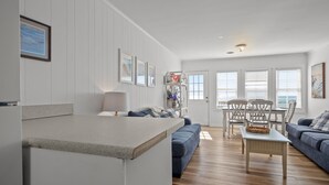 A spacious living area with a kitchen counter, a dining table with chairs, and a sofa. - Classic Oceanfront Beach Cottage! (Emerald Isle)